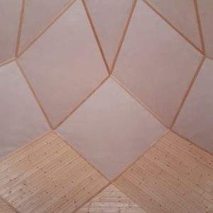 Intérieur dun hébergement en bois, avec un plafond géométrique lumineux.