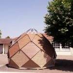 Hébergement touristique en forme de dôme, en bois, entouré darbres.