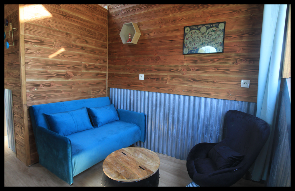 1 Hébergement insolite en Midi-Pyrénées : salon cosy avec canapé bleu et murs en bois.