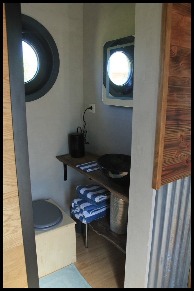 12 Hébergement insolite à Midi-Pyrénées : intérieur moderne avec lavabo et fenêtre ronde.