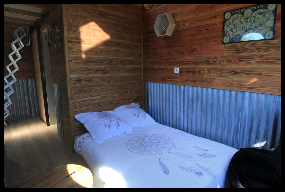 2 Chalet en bois avec lit douillet et décoration en métal, ambiance chaleureuse.