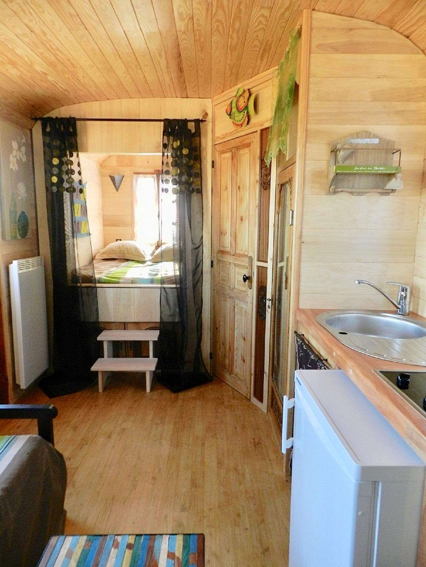 R2 (1) Hébergement insolite en roulotte, intérieur en bois chaleureux avec kitchenette.