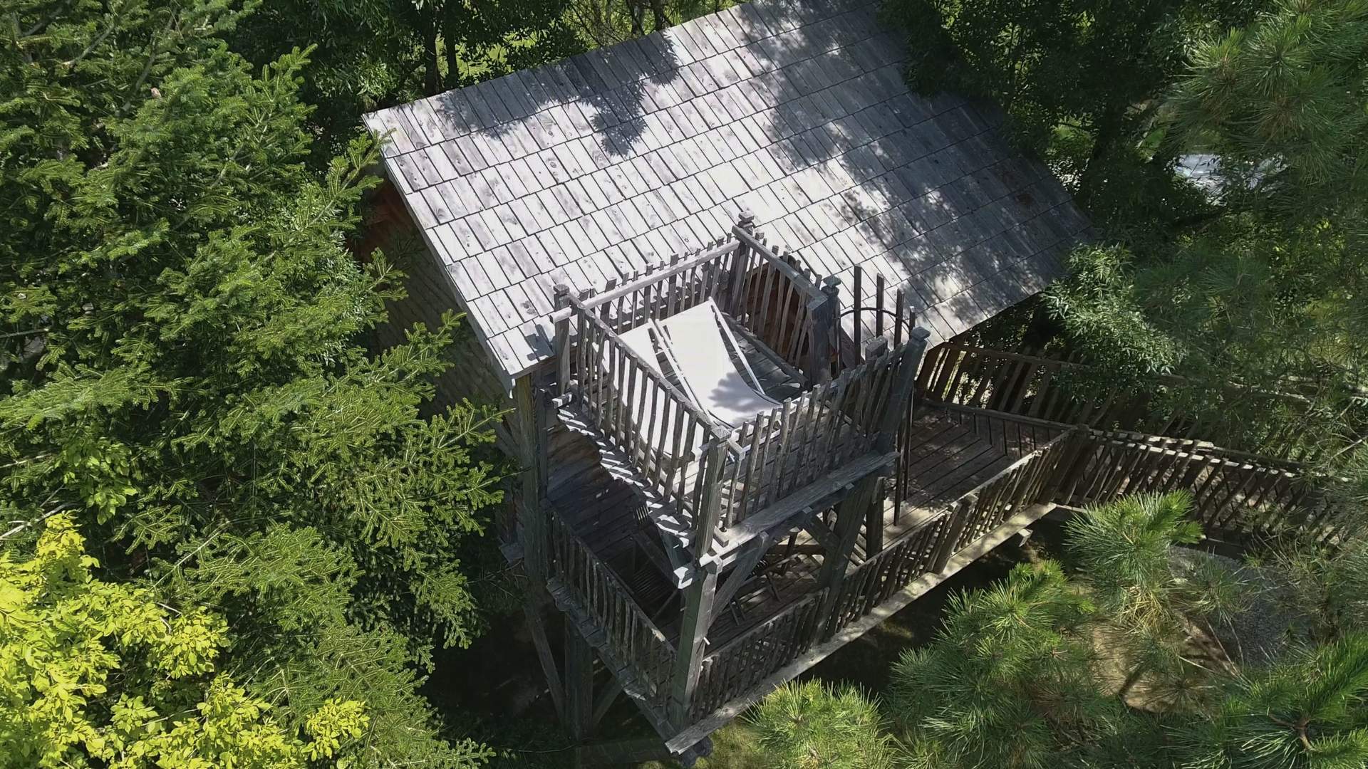 Cabane Palombiere 11 Cabane perchée en bois, entourée darbres, avec une terrasse ensoleillée.