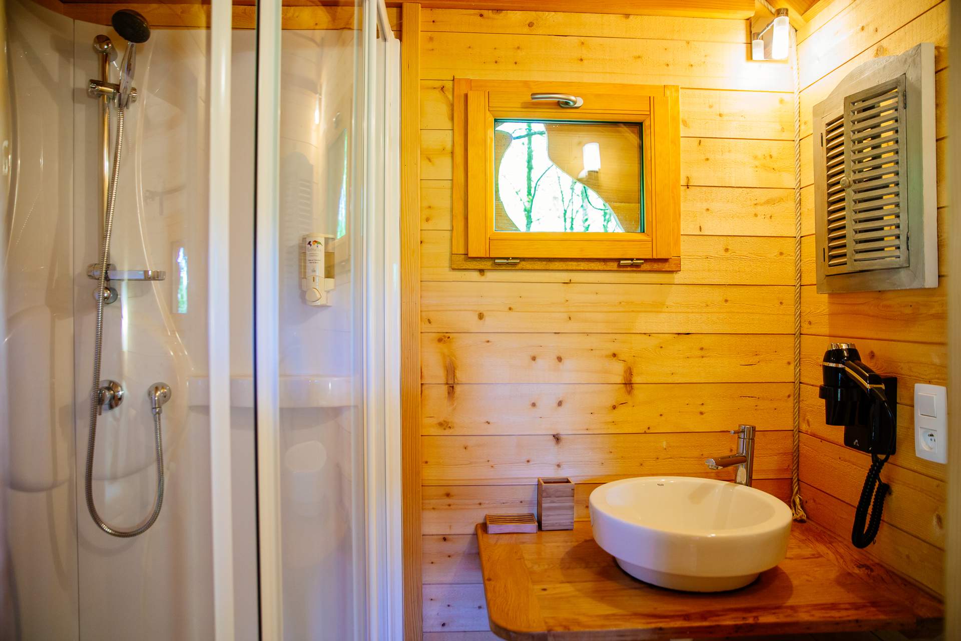 Cabane Palombiere 6 Cabane en bois avec salle de bain moderne et fenêtre sur la nature.