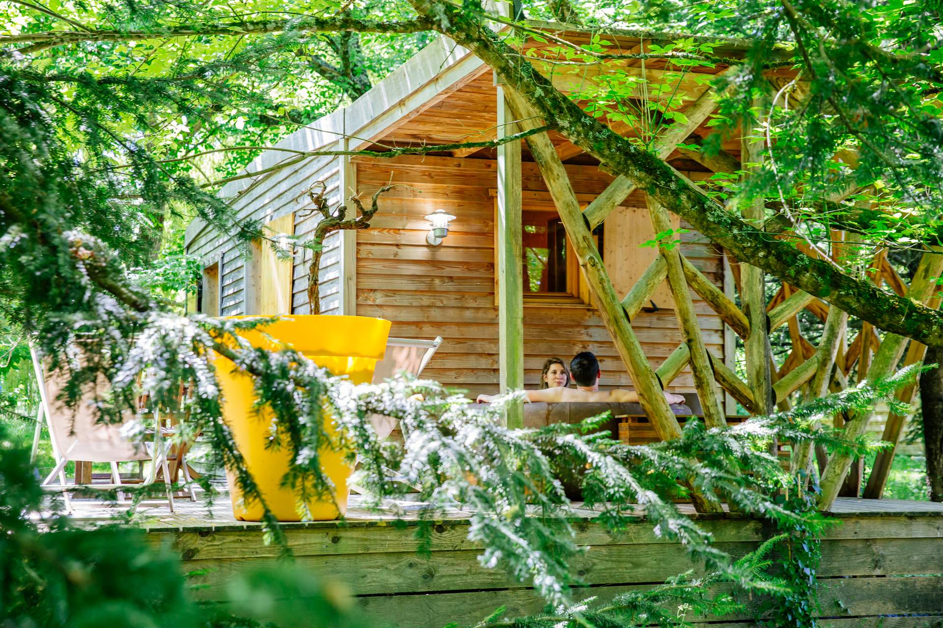 Oenolodge avec spa 2 Cabane perchée en Aquitaine, entourée de verdure, avec terrasse en bois accueillante.