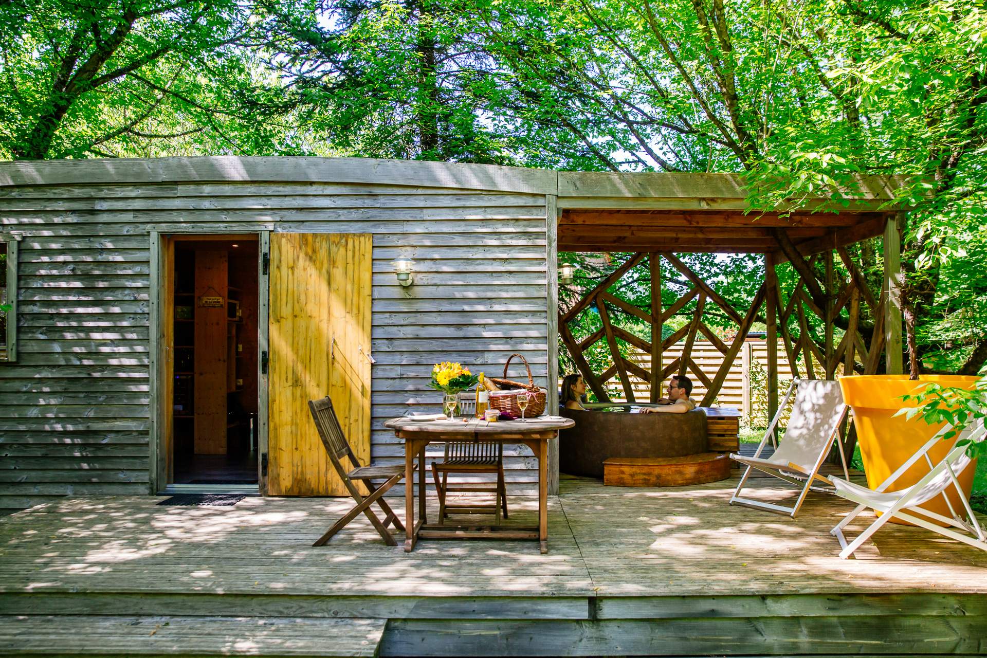 Oenolodge avec spa 3 Cabane en bois dans les arbres, avec terrasse en bois et mobilier extérieur.