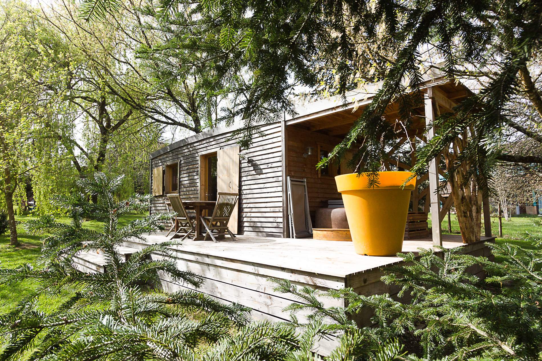 Oenolodge avec spa 9 Cabane en bois nichée dans la verdure, avec une grande jardinière orange.