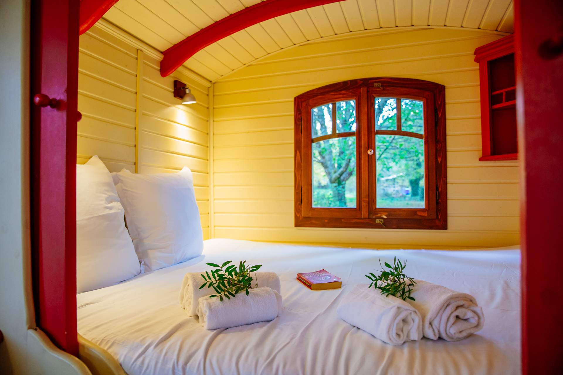 Roulotte Tzigane 6 Hébergement insolite en Aquitaine : une charmante roulotte avec lit douillet et fenêtres en bois.