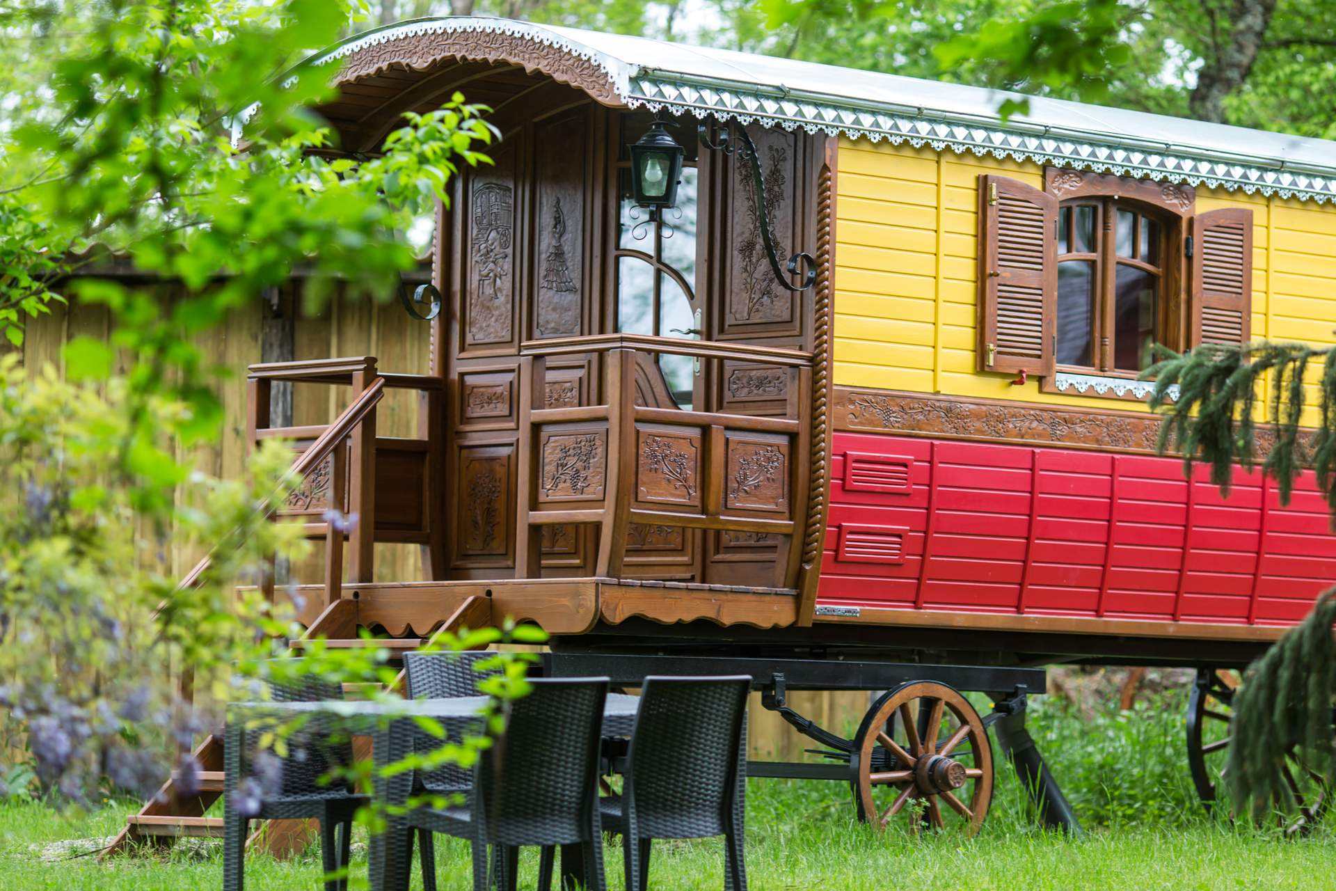 Roulotte Tzigane 8 Charmante roulotte colorée avec balustrade en bois, entourée de verdure en Aquitaine.