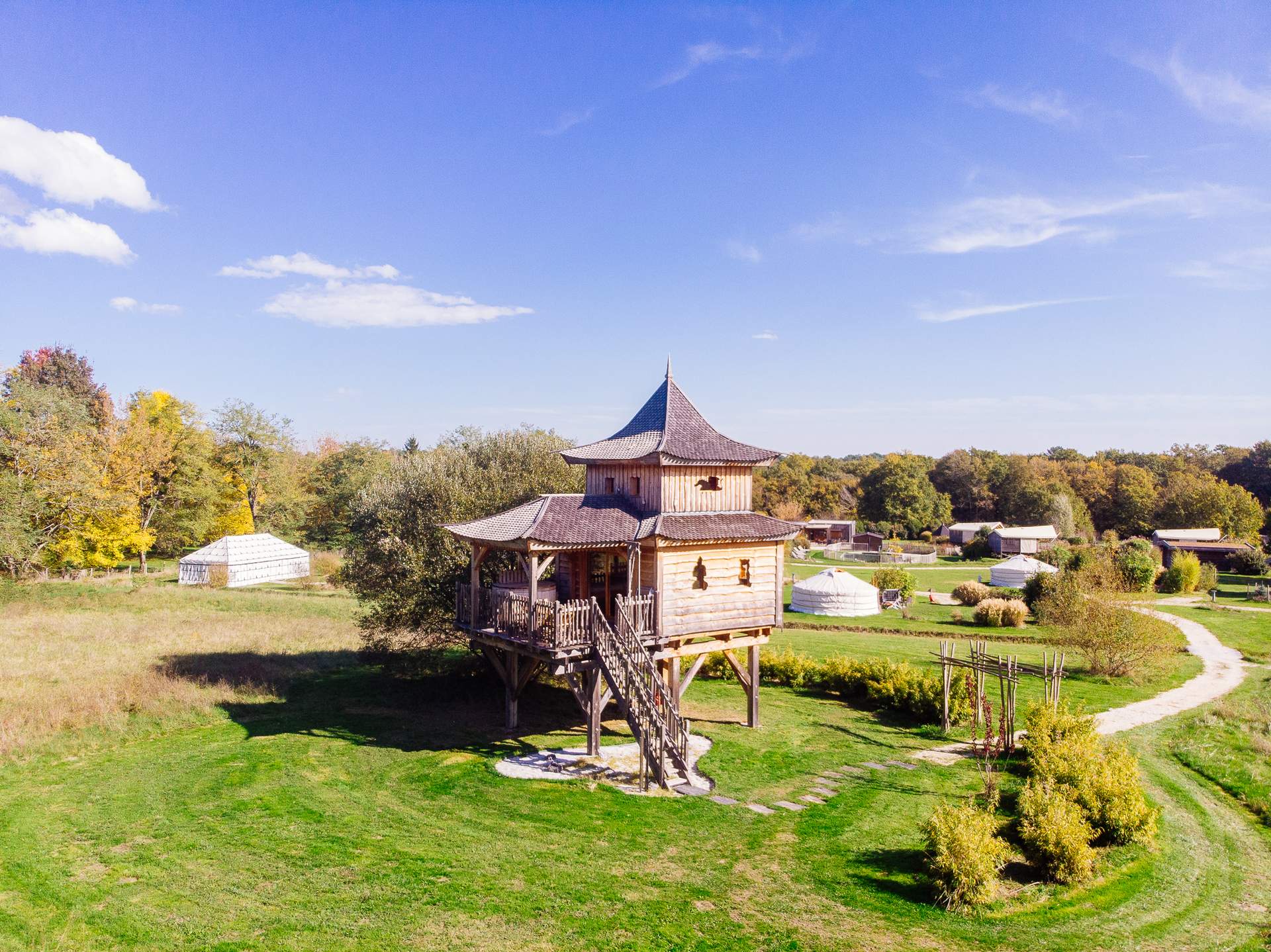 Temple perche avec spa 12 Cabane en bois perchée, entourée de verdure et dun ciel bleu éclatant.