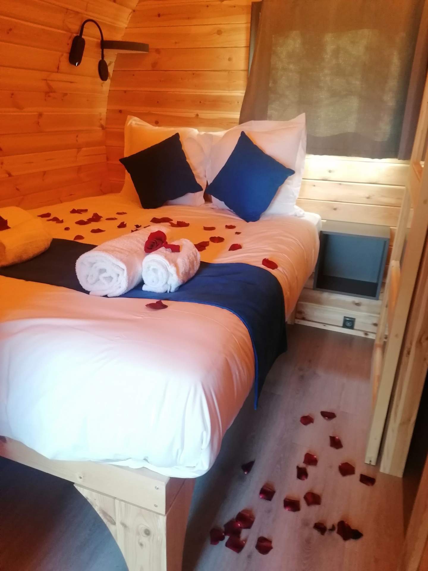 Chalet en bois romantique avec pétales de rose sur le lit et ambiance chaleureuse.