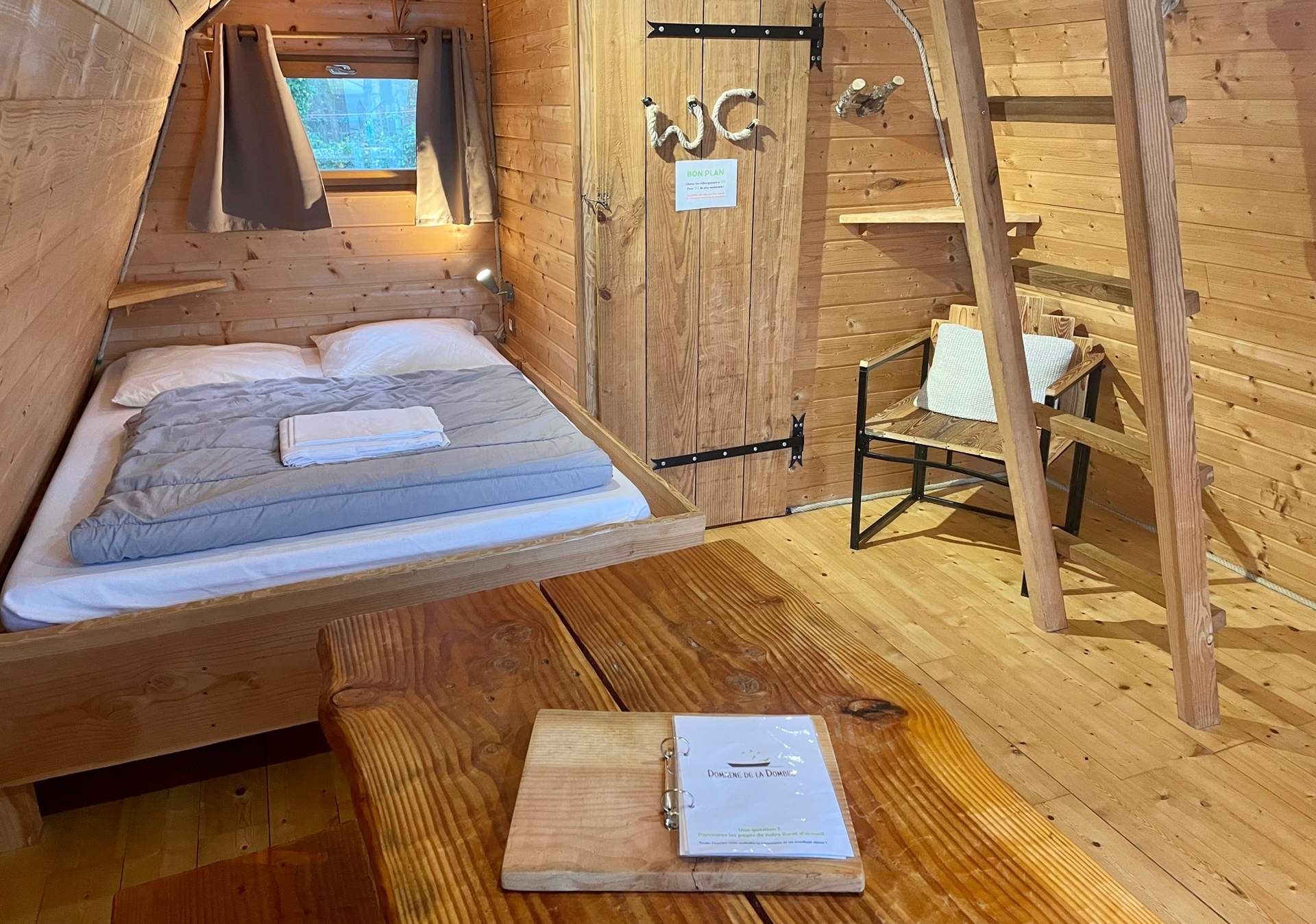 IMG_7465 Chalet en bois cosy avec lit double et table en bois, ambiance chaleureuse.