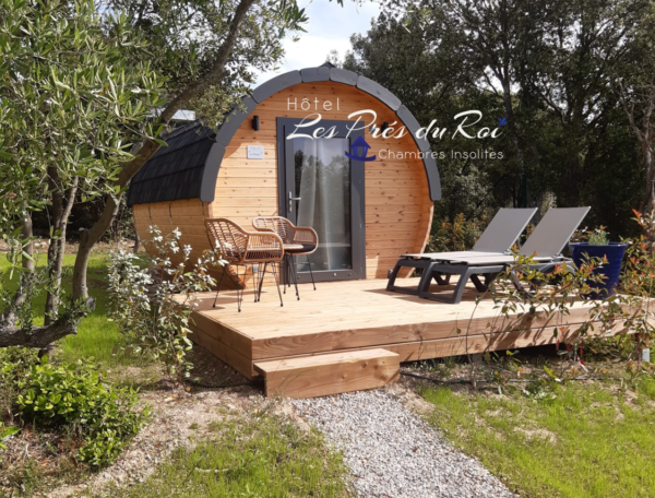 Hébergement insolite en forme de tonneau, avec terrasse et chaises longues.