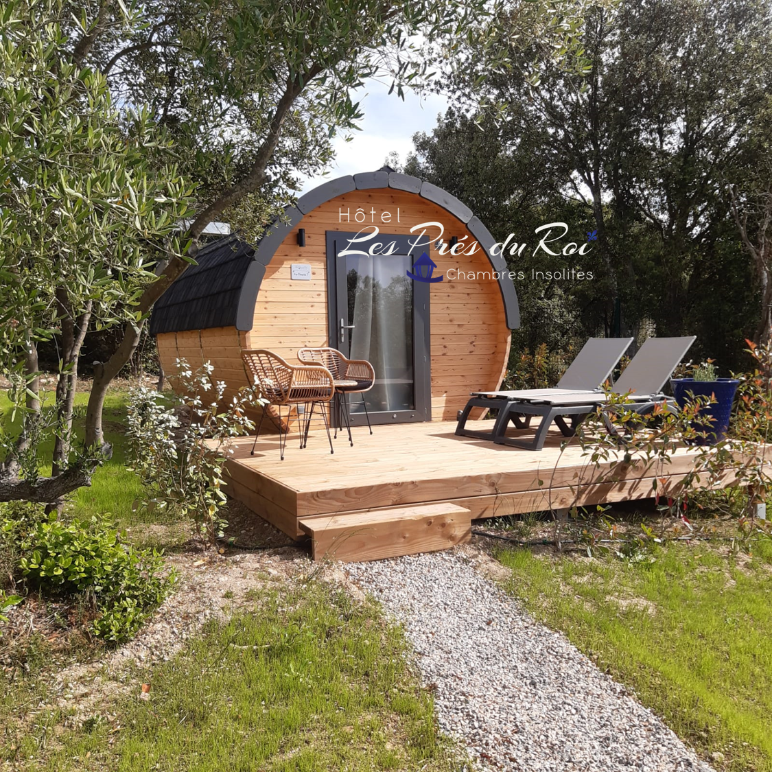 Hébergement insolite en forme de tonneau, avec terrasse et chaises longues.
