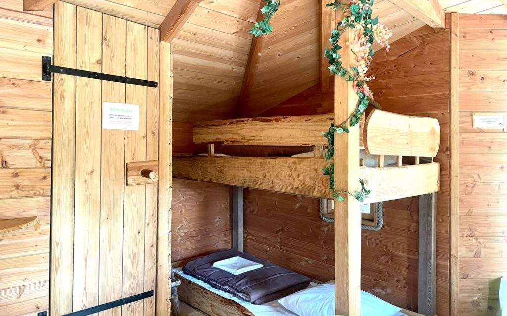 feuilles Cabane en bois avec lits superposés et décoration végétale chaleureuse.