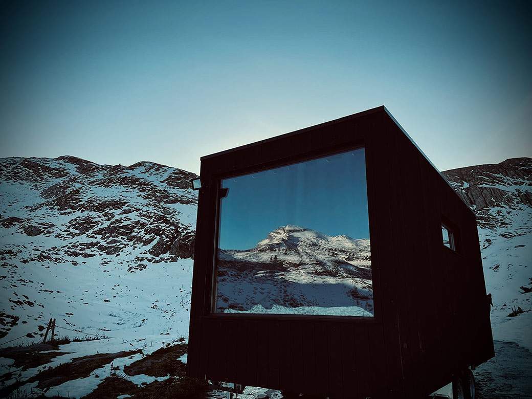Cabane moderne en bois avec grande fenêtre, vue sur montagnes enneigées en Aquitaine.
