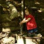 Hébergement rural avec un puits en bois, enfant jouant près de leau.