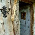 Cabane en bois rustique avec une porte ancienne et des appliques murales.