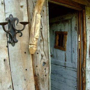 Cabane en bois rustique avec une porte ancienne et des appliques murales.