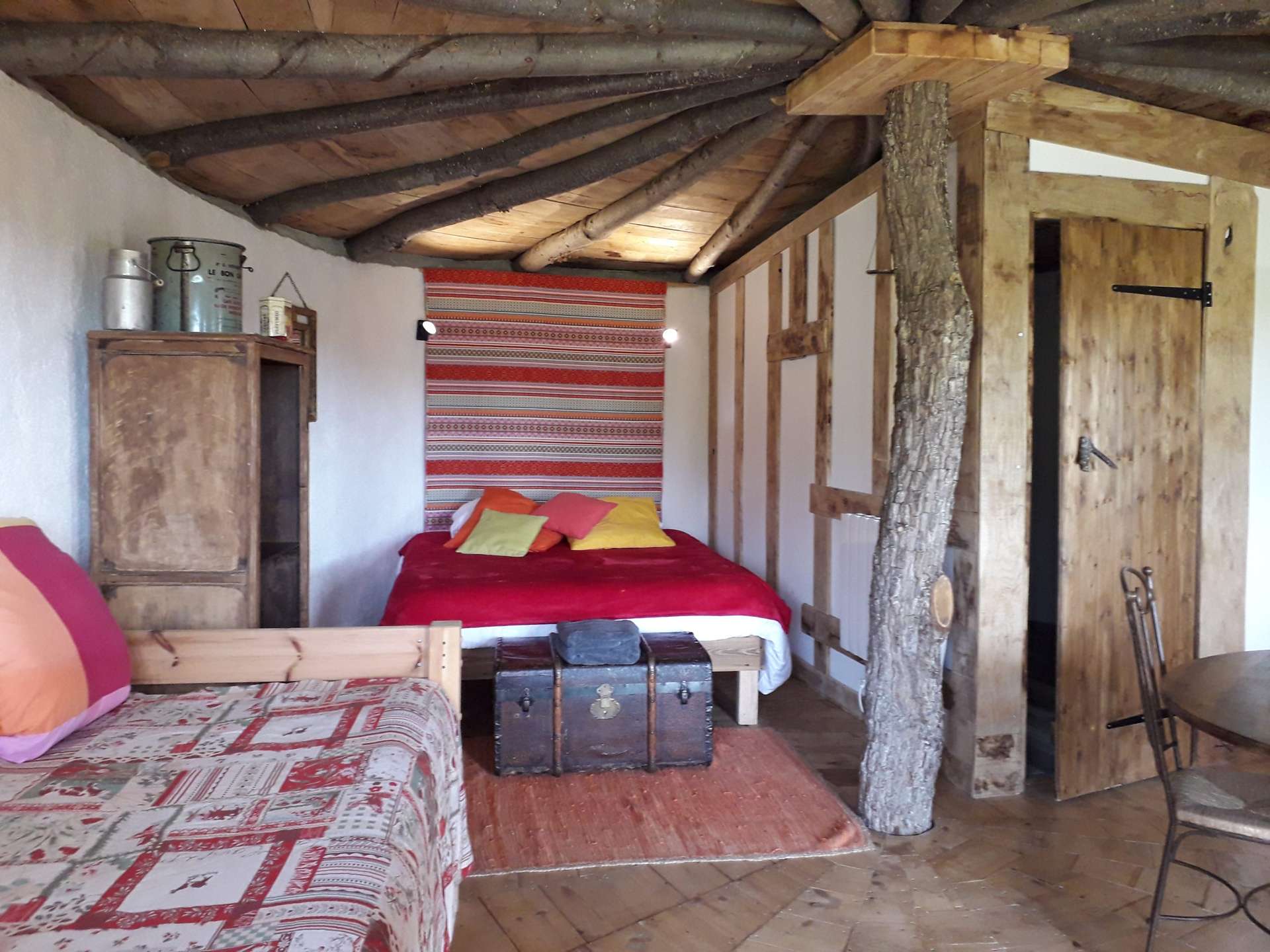 20201217_101044 Chalet en bois avec un lit douillet et des touches colorées sur les coussins.