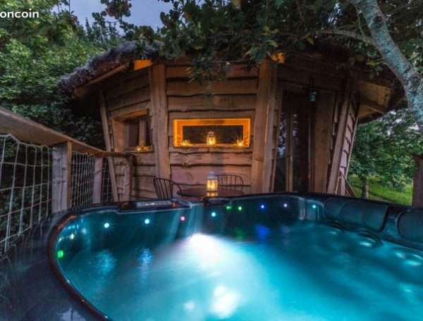 Cabane en bois avec jacuzzi lumineux, nichée dans la verdure à Midi-Pyrénées.