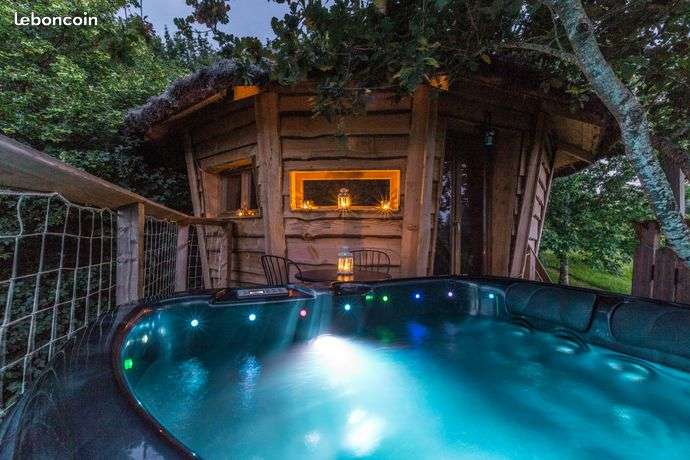 Cabane en bois avec jacuzzi lumineux, nichée dans la verdure à Midi-Pyrénées.