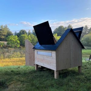 Cabane en bois avec toit ouvrant, située dans un cadre verdoyant et paisible.