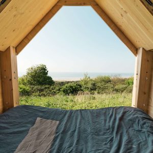 Cabane en bois avec vue panoramique sur la nature, lit confortable à lintérieur.