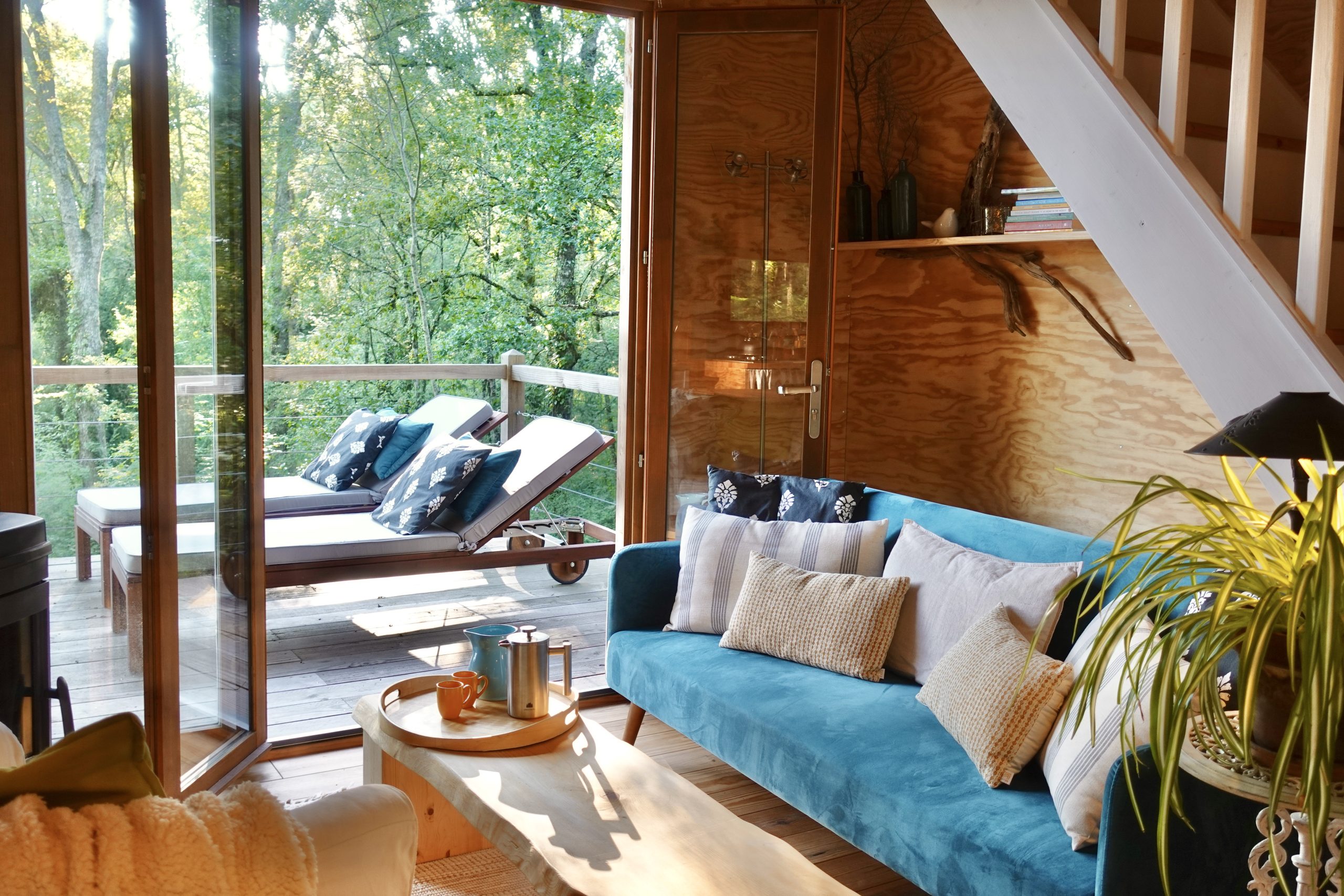 Cabane en bois avec terrasse, salon lumineux et vue sur la nature verdoyante.