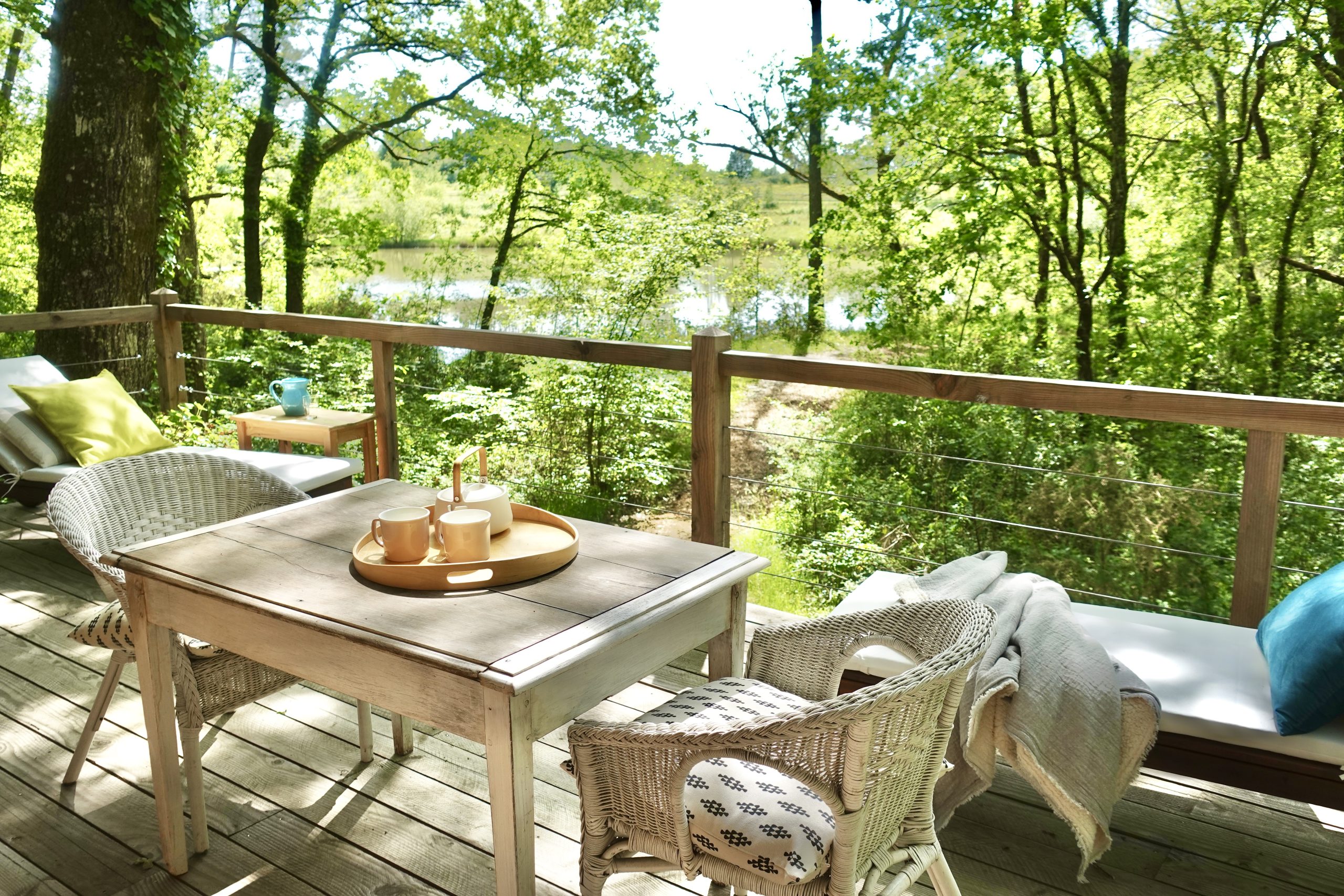 Cabane en bois avec terrasse, vue sur la nature verdoyante et le lac.