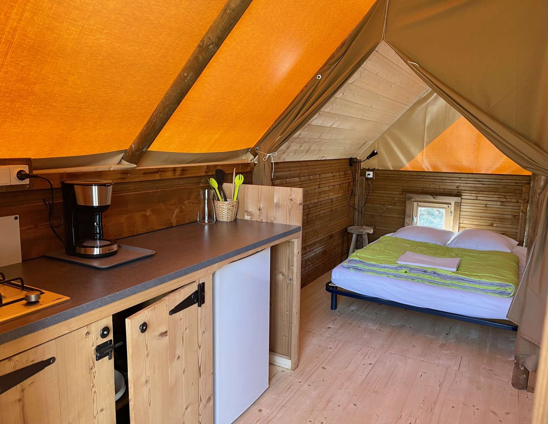 IMG_3715 Tente lodge confortable en Auvergne-Rhône-Alpes, avec intérieur en bois et lumière naturelle.