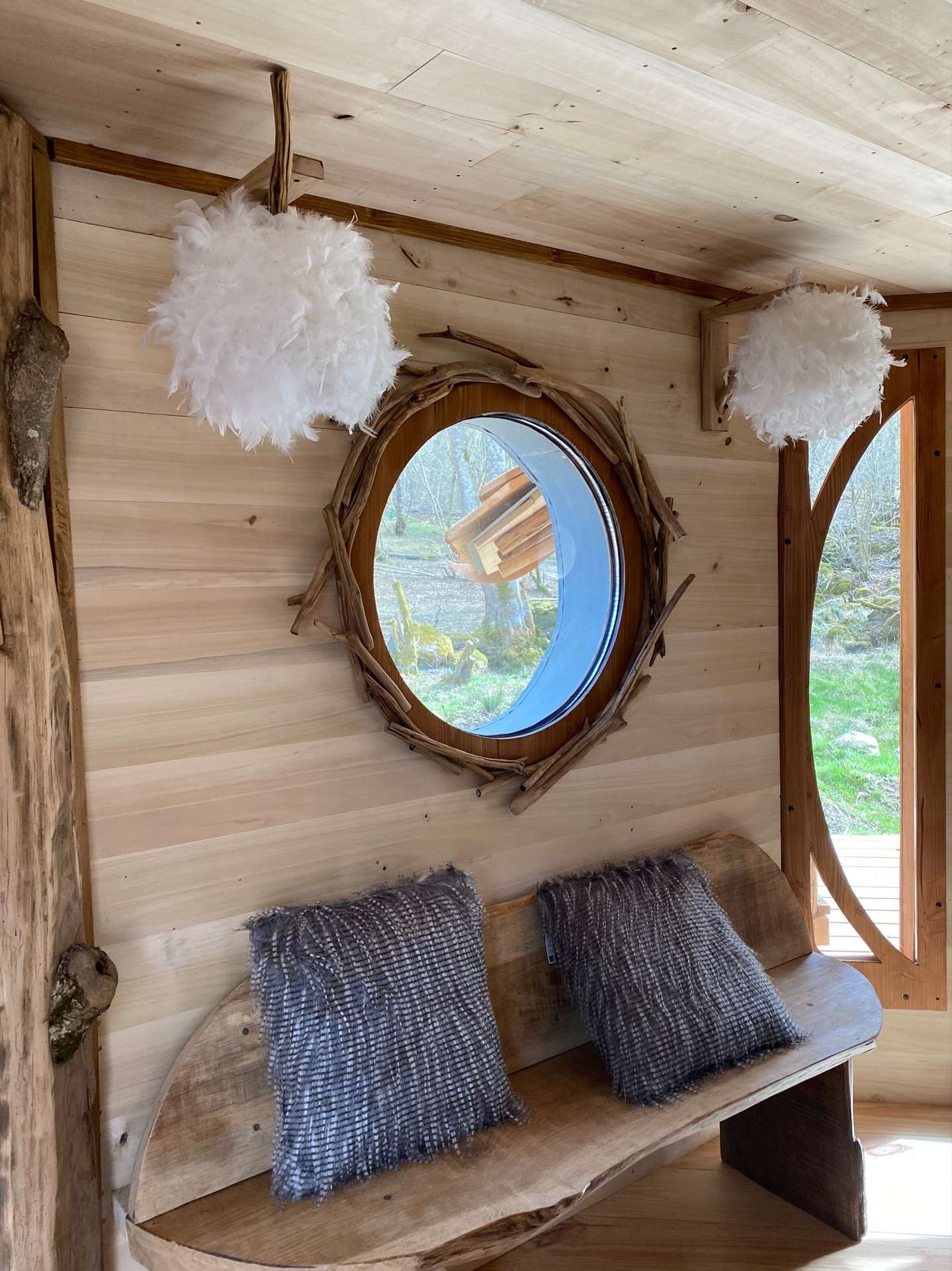IMG_4324 Hébergement insolite en Midi-Pyrénées, intérieur en bois avec miroir rond et coussins moelleux.