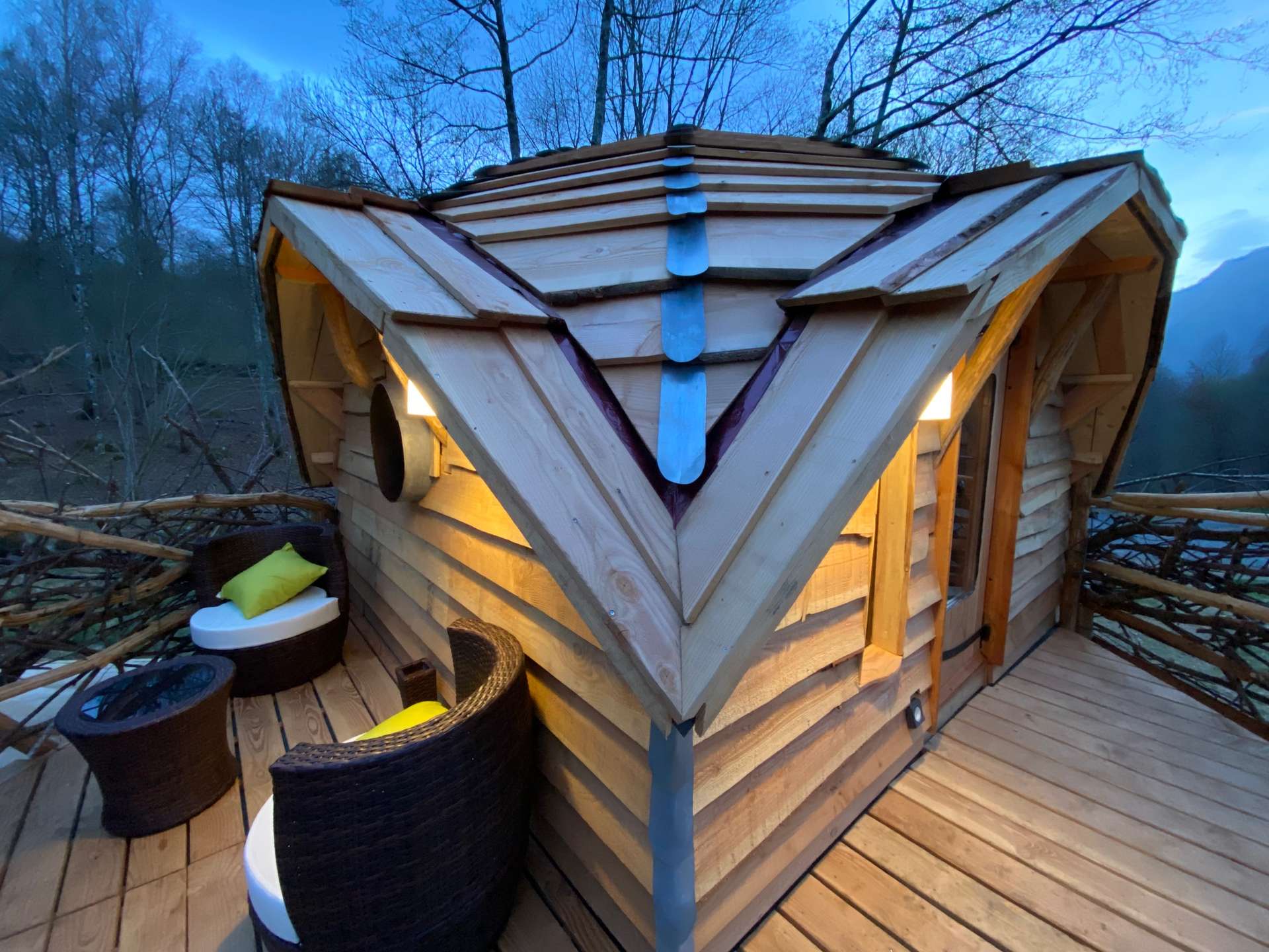 IMG_4596 Cabane en bois perchée, toit en pente, avec terrasse et fauteuils confortables.