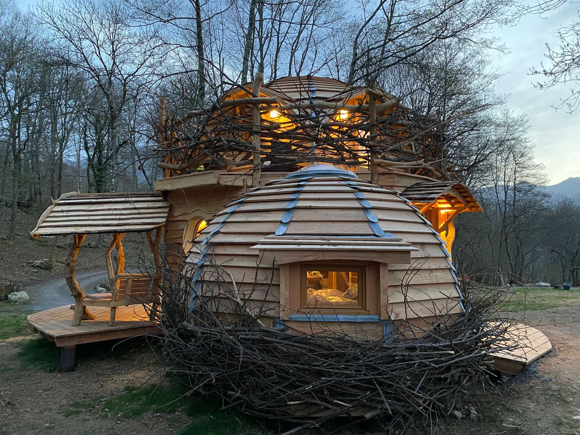 IMG_4603 Cabane en bois originale à Midi-Pyrénées, entourée de branches naturelles.