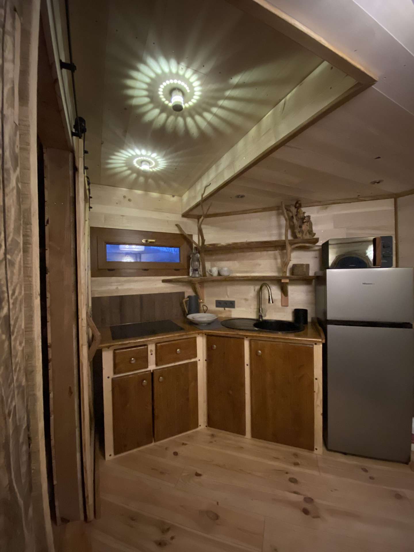 IMG_4614 Hébergement insolite en Midi-Pyrénées, intérieur en bois avec cuisine équipée et éclairage design.