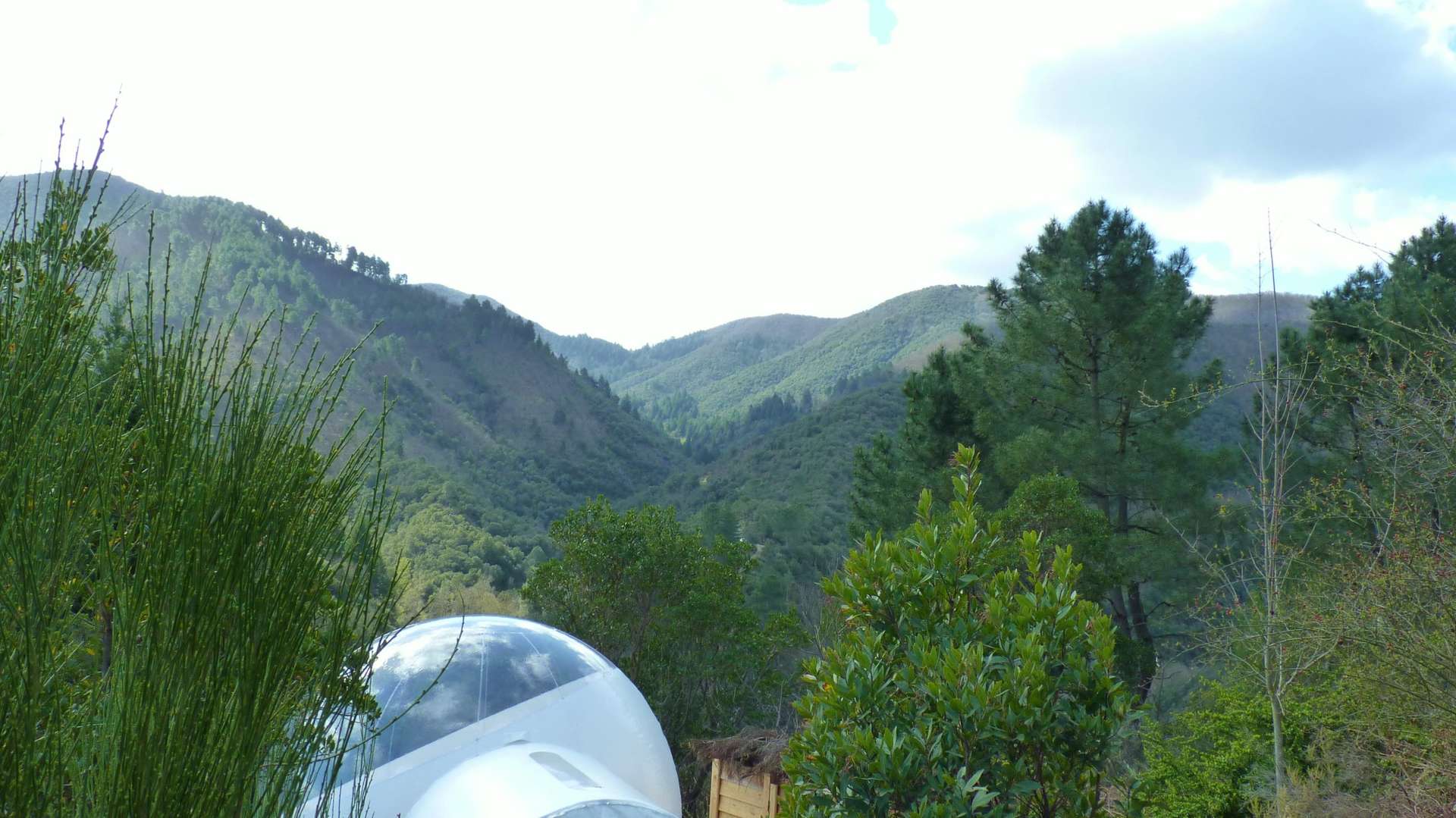 P1000363 Hébergement insolite en bulle transparente, avec vue sur les montagnes verdoyantes.