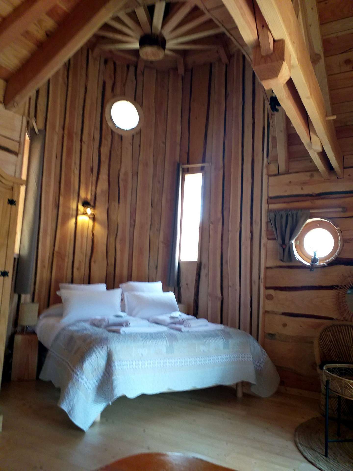 20220514_152026 Chalet en bois dans les montagnes, avec un lit douillet et des fenêtres rondes.