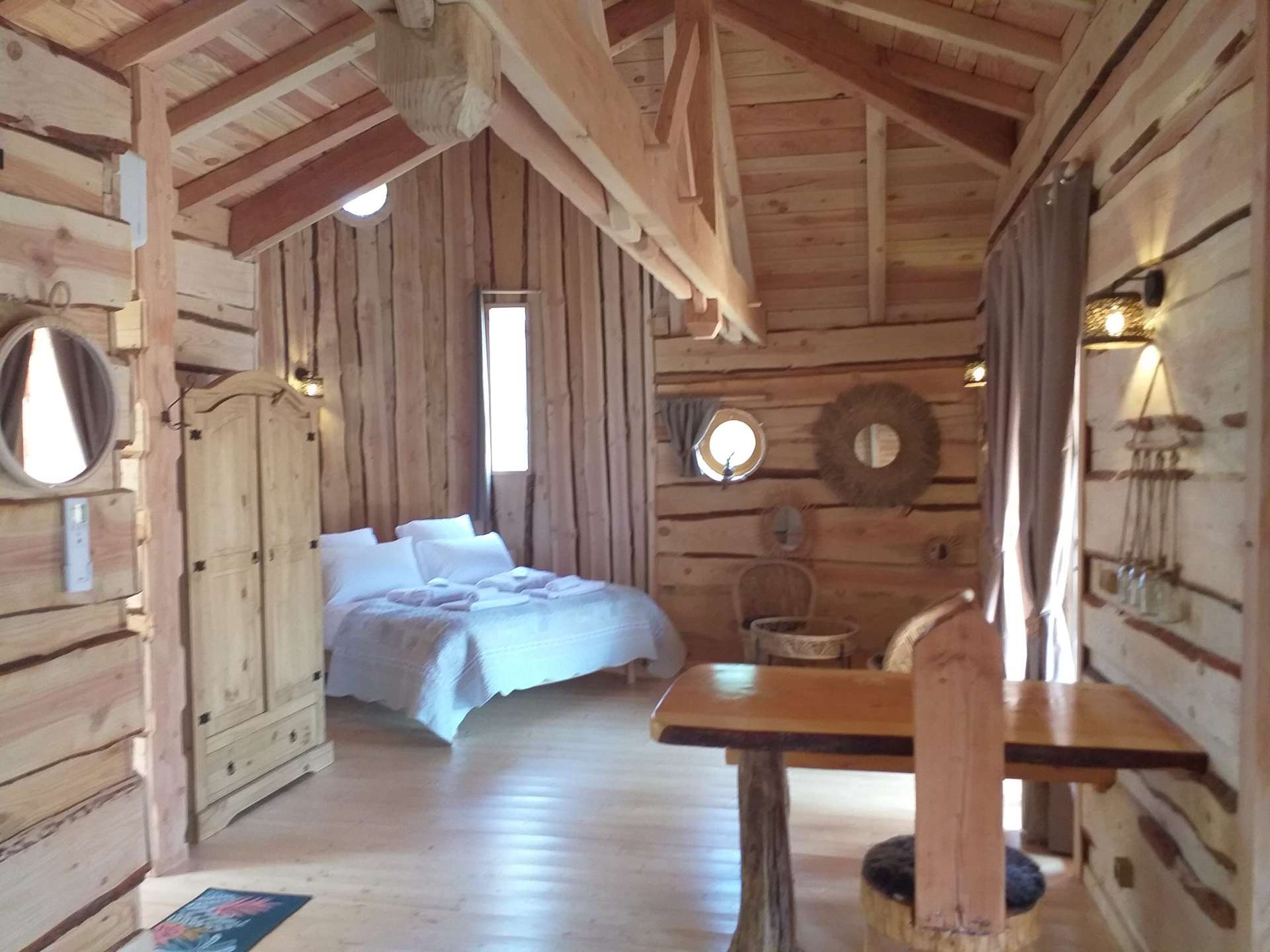 20220514_152113 Cabane en bois dans les montagnes, intérieur chaleureux avec lit douillet et lumière naturelle.