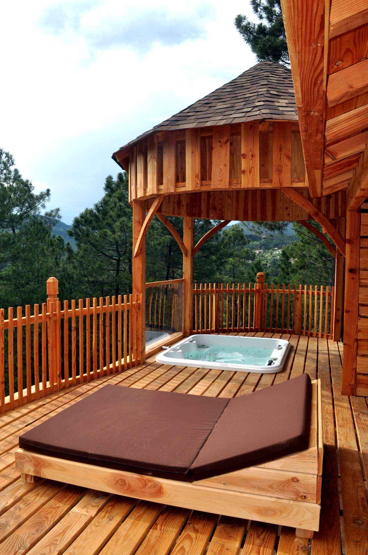 DSC_0118 Cabane en bois avec jacuzzi sur une terrasse ensoleillée, vue sur la nature.
