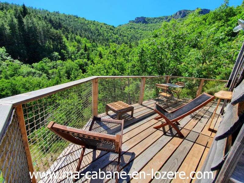 20220529_154535_resultat Cabane perchée en Languedoc-Roussillon avec terrasse en bois et vue sur la nature verdoyante.