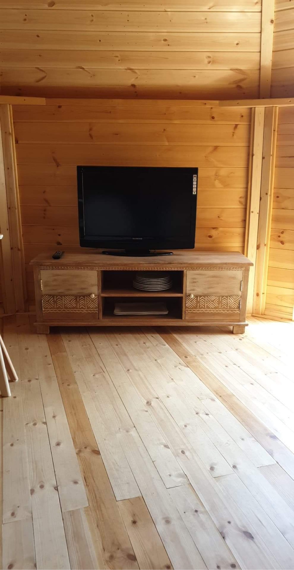 3B1CA8BC-0B1E-45ED-8BF4-805D51848724 Hébergement insolite en bois avec un intérieur chaleureux et un téléviseur moderne.