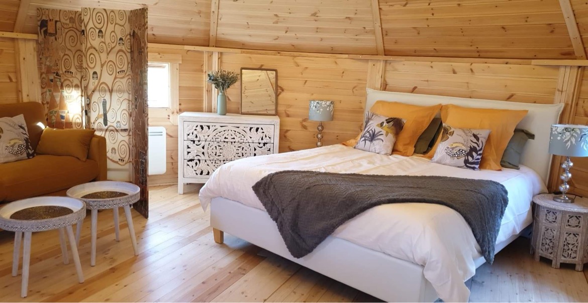 6E79A1F2-2A11-4BAB-82DD-D4750BF1FB3E Hébergement insolite en cabane avec lit douillet et décor en bois chaleureux.