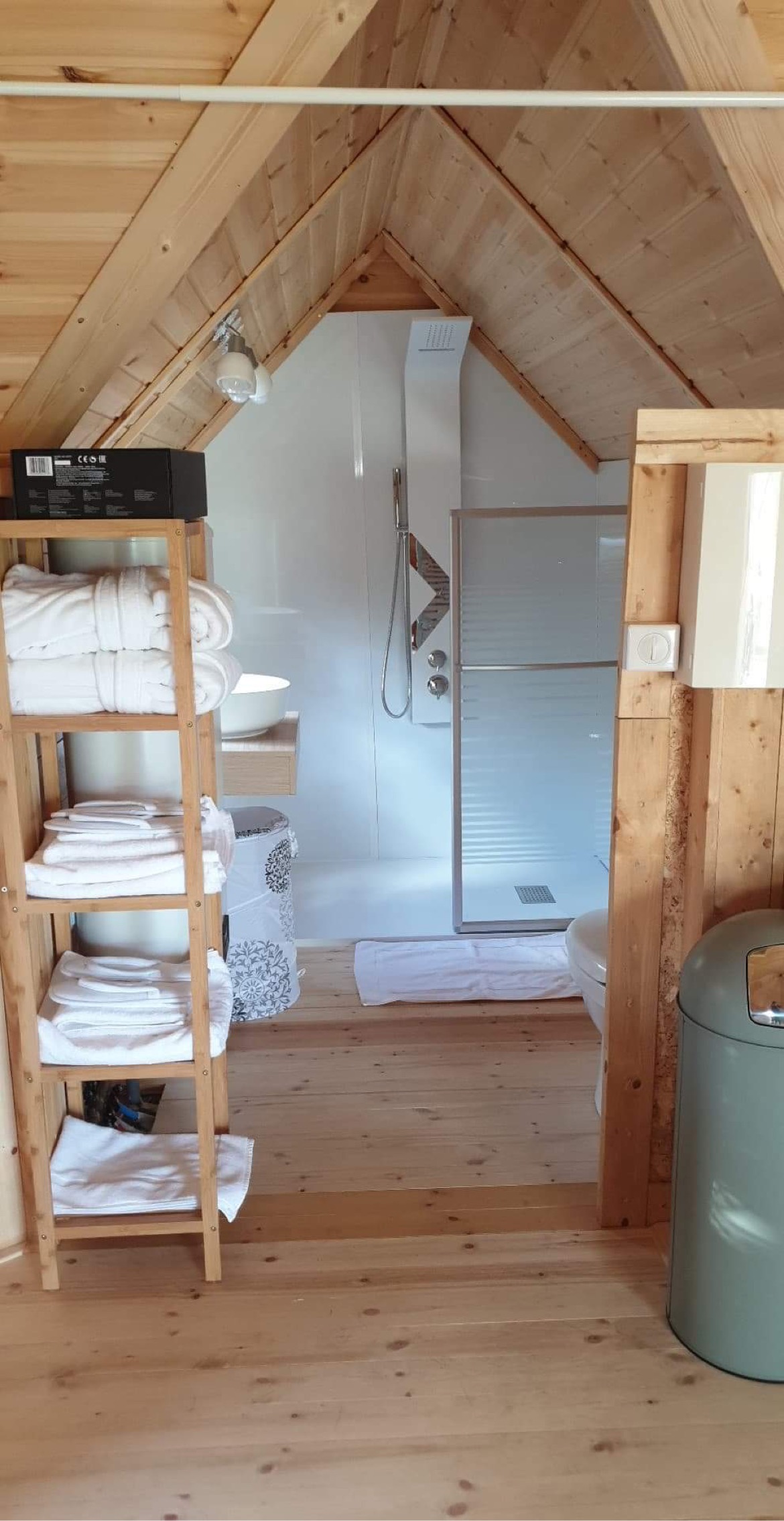 DED0CC2A-3FFC-492D-979C-4DC631267B4D Cabane en bois avec salle de bain moderne et linge de maison soigneusement rangé.
