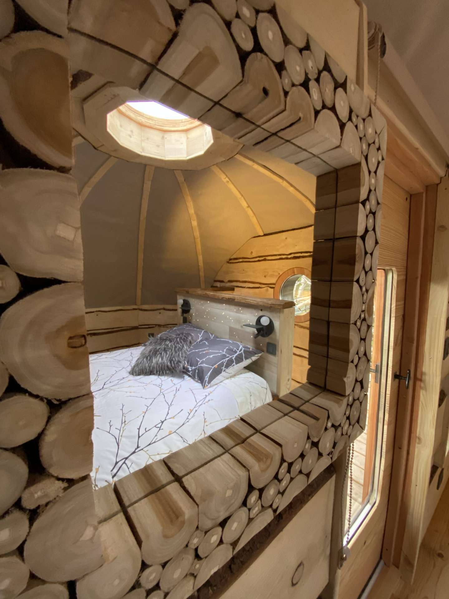IMG_5455 Cabane en bois avec un lit douillet et un miroir en rondins décoratif.
