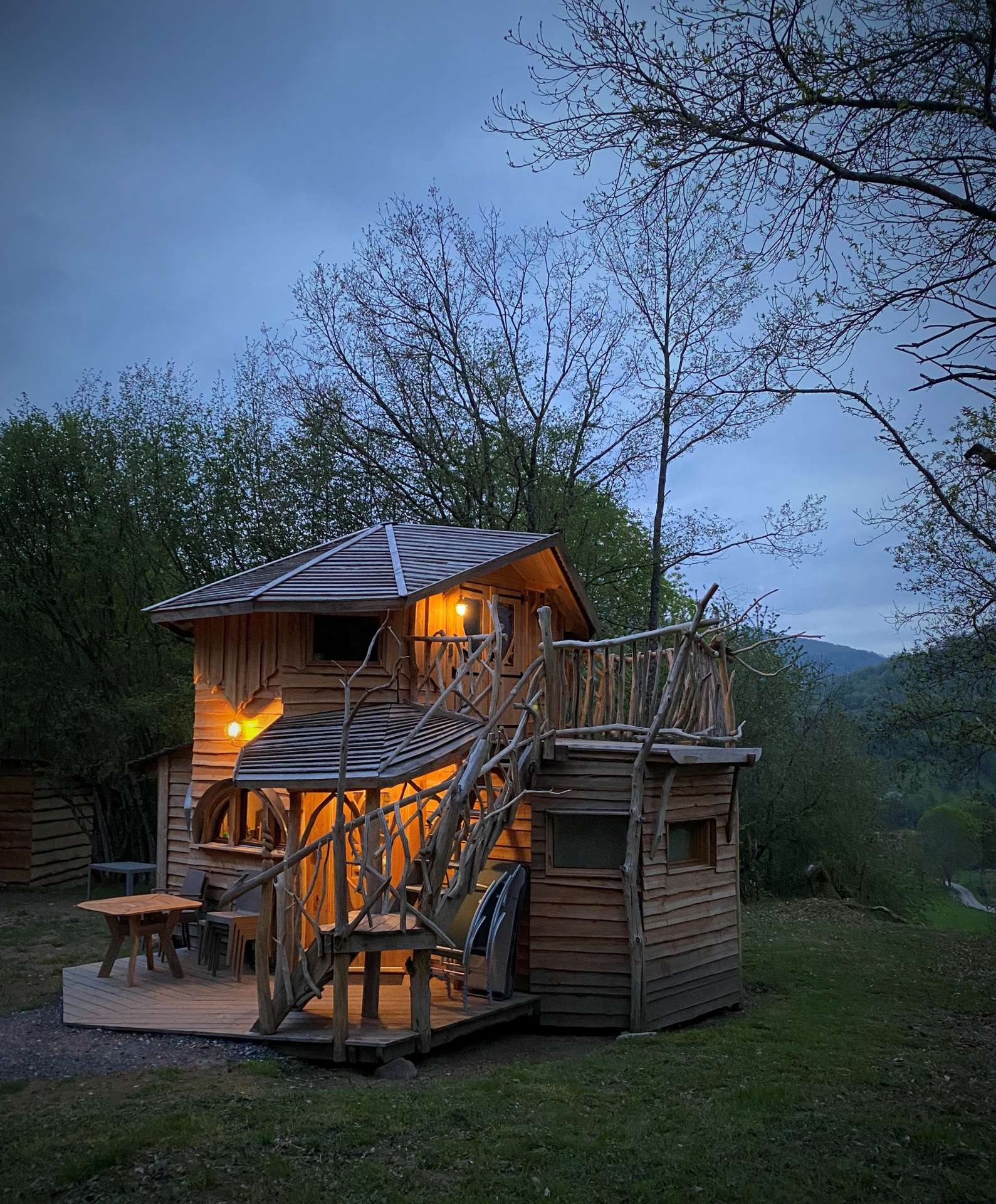 IMG_5528 Cabane dans les arbres à Midi-Pyrénées, éclairée, entourée de verdure.
