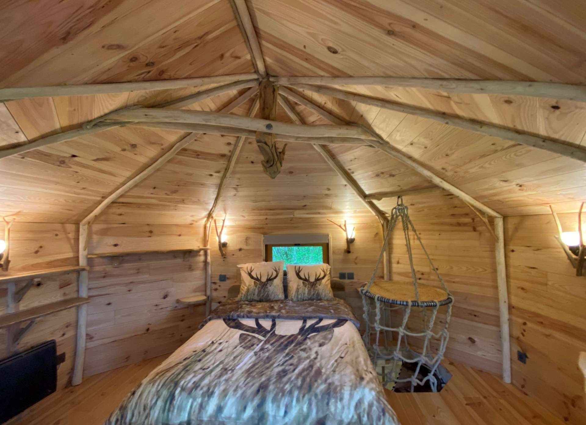IMG_5589 Cabane en bois avec intérieur chaleureux, lit confortable et décor naturel.