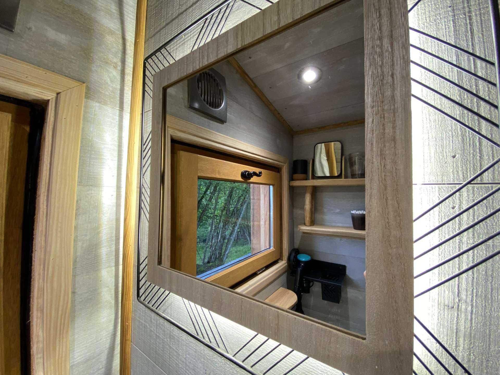 IMG_5726 Cabane moderne en bois avec un miroir décoratif et vue sur la nature environnante.