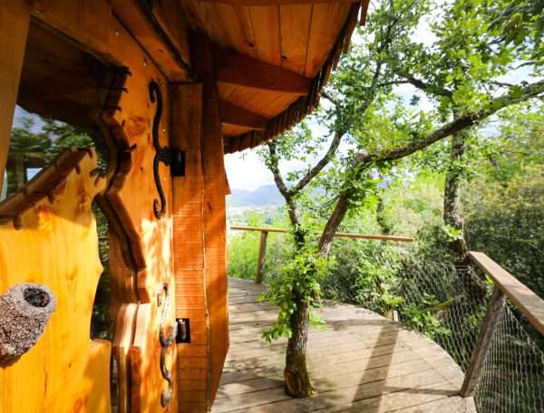 Cabane perchée en bois, entourée darbres, offrant une vue imprenable sur la nature.