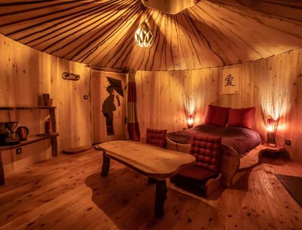 Hébergement insolite : yourte en bois avec lit douillet et ambiance chaleureuse.