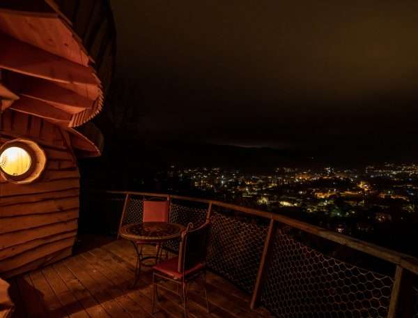 Cabane perchée à Languedoc-Roussillon, vue nocturne sur la ville illuminée.